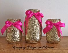 three jars with pink bows are sitting on a table