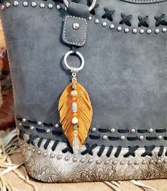 a handbag with a feather charm hanging from it's side