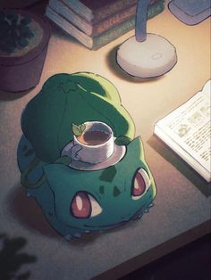 a green pokemon pillow sitting on top of a table next to a book and lamp