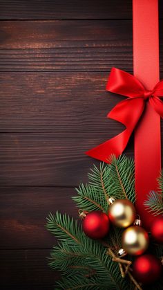 a red bow and some christmas decorations on a wooden table with pine branches, balls and baubles