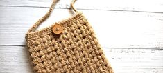 a crocheted purse sitting on top of a white wooden floor next to a button