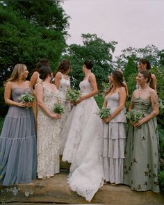 a group of women standing next to each other on top of a wooden platform in front of trees