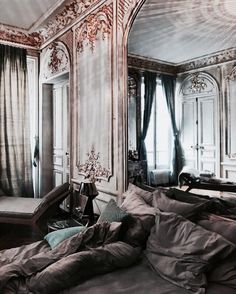 a large bed sitting in the middle of a bedroom next to a tall window with curtains