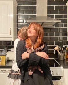 two people standing in a kitchen next to each other with their arms around one another