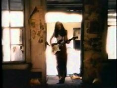 a woman standing in front of a doorway with an electric guitar