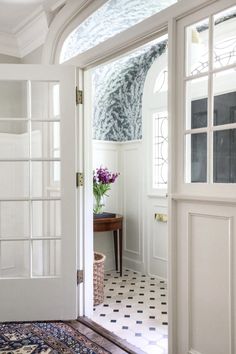 an open door leading into a white room with black and white checkered flooring