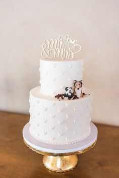 a wedding cake with two dogs on top and the bride and groom's initials