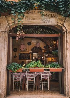 a restaurant with tables and chairs in front of an arched doorway that has ivy growing on it