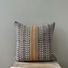 a pillow sitting on top of a wooden table next to a gray and yellow wall