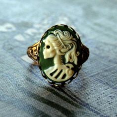 18x13mm green and cream acrylic skeleton lady cameo.On an antiqued brass cigar band style ring. Easy to adjust to most sizes.Let me know if you'd rather this on an antiqued silver plated ring band. See other color options in the last photo. Antique Silver Rings, Steampunk Accessories, Cameo Jewelry, Cameo Ring, Funky Jewelry, Skull Tattoos, Fun Gifts, Halloween Jewelry, Black And Brass