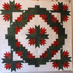 a quilted wall hanging with red, green and white designs on it's sides