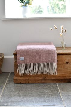 a pink blanket sitting on top of a wooden chest