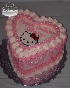 a heart shaped cake with hello kitty on it's side and pink icing