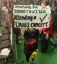 a woman holding up a sign that says studying for tomorrow is just attending a louis's concert