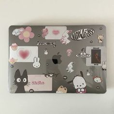 an open laptop computer sitting on top of a white table covered in stickers and decals