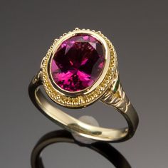 Exquisitely handcrafted in granulated 18KY gold, the “flower” of this one-of-a-kind ring is a 3.13ct rubellite tourmaline. Butterflies created in 18KW and each set with a 1.3mm VS/GH diamond are found on either side of the center gemstone. 2mm tsavorite garnets and the engraved leaf pattern create the flower’s stalk on the shank as engraved butterflies on the shank and beneath the center stone all flutter to the dazzling raspberry-red of the luscious rubellite tourmaline. Size 5.5, but each ring Luxury Tourmaline Rings With Halo Setting, Formal Ruby Ring With Tourmaline Accents, Oval Tourmaline Ruby Ring For Formal Occasions, Luxury Yellow Gold Tourmaline Emerald Ring, Oval Ruby Ring With Gemstone Accents In Yellow Gold, Formal Oval Tourmaline Ruby Ring, Formal Oval Ruby Ring With Tourmaline, Formal Yellow Gold Emerald Ring, Elegant Ruby Birthstone Ring With Tourmaline