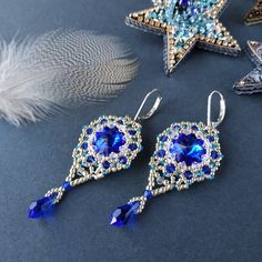 two pairs of blue crystal earrings on a table next to a feather and star ornament