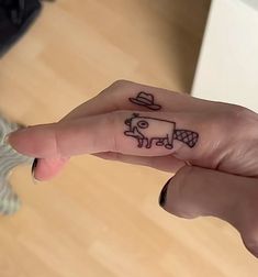 a person's hand with a small tattoo on the middle finger that has a cow drawn on it