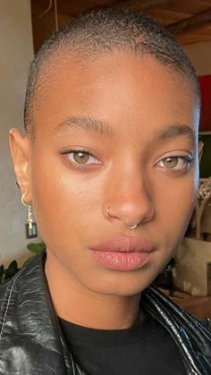 a close up of a person wearing a black leather jacket and piercing on her nose