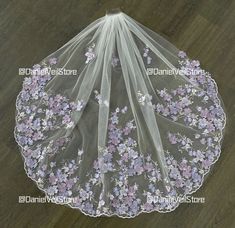 a veil with flowers on it sitting on top of a wooden floor