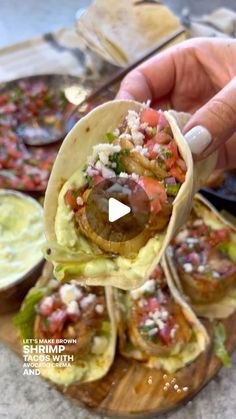 a person holding up a tortilla filled with meat and vegetables on a wooden platter