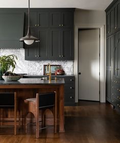 a kitchen with dark green cabinets and wooden floors