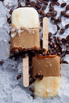 three ice cream pops with chocolate and coffee beans on the top one is cut in half