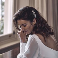 a woman in a white dress is talking on her cell phone while sitting at a table