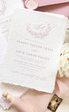 the wedding stationery is laid out on top of pink and white paper with flowers