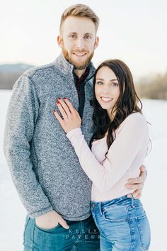 a man and woman are standing in the snow with their arms around each other smiling