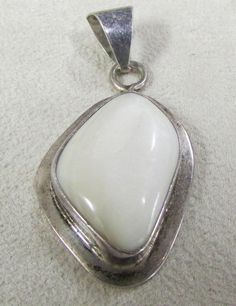 "Sterling silver and mother of pearl pendant. Stamped TJ-76 MEX 925. 1 1/4\" tall x 15/16\" tall. The ring and bail add 5/8\" to the height. The shell has a subtle shine to it. Good condition with natural patina. PWS-2" White Oval Pendant With Polished Finish, White Mother Of Pearl Pendant Jewelry, White Teardrop Jewelry With Polished Finish, Polished Mother Of Pearl Pendant Jewelry, White Hallmarked Oval Pendant Jewelry, Elegant Untreated White Jewelry, Unique White Jewelry With Polished Finish, Silver Mother Of Pearl Shell Jewelry, White Oval Pendant Jewelry Stamped 925