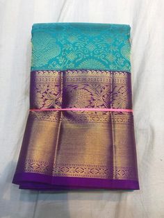 two pieces of blue and purple silk saree on a white sheet with pink border