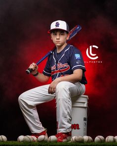 a young baseball player sitting on top of a bucket with a bat in his hand