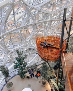 the inside of a building with lots of plants and people sitting at tables in it