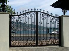 an iron gate on the side of a road with a car parked in front of it