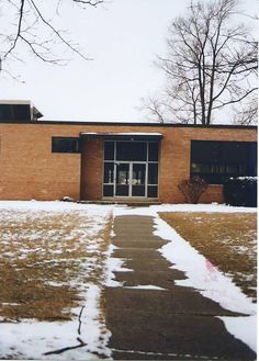 a brick building with snow on the ground and trees in the background