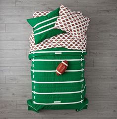 a bed with green and white comforter, pillows and pillow cases on top of it