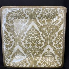 a white and gold plate with an ornate design on it's side, against a black background