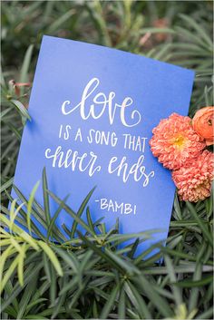 a blue card with the words love is a song that never ends on it next to some flowers