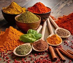 various spices and herbs in wooden spoons on a table