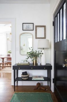 an entryway with a black table, mirror and rug on the floor next to it