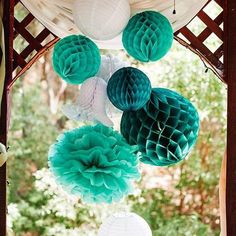 tissue balls and honeycombs decorate the gazebo for an outdoor wedding in teal