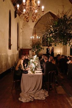 a group of people sitting around a table in a room with chandeliers hanging from the ceiling