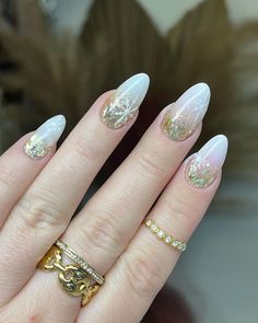 Almond nails with frosted white tips and gold glitter create an ethereal, wintery feel. Delicate snowflakes add a magical touch to the design, making it perfect for holiday gatherings or winter weddings. The frosted look evokes a snowy landscape, blending elegance with a hint of seasonal sparkle. Gold Christmas Nail Designs, Gold Christmas Nails, White Tips, Snowy Landscape, White Tip, Winter Weddings