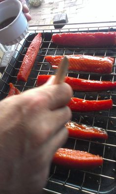 someone is cooking red peppers on the grill