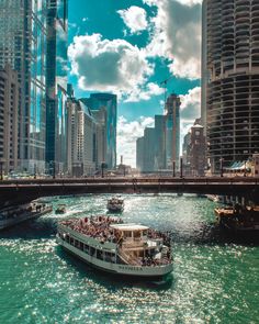 a boat full of people is going down the river in front of some tall buildings