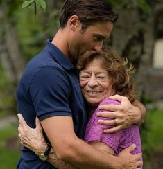 a man and woman hugging each other in the park