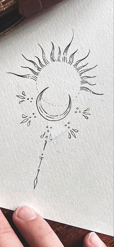 a person holding up a piece of paper with a drawing on it and the sun in the background