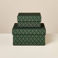 three green boxes are stacked on top of each other, one with white and red flowers