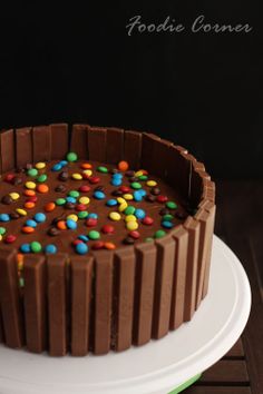 a chocolate cake with candy and sprinkles on the top is sitting on a white plate